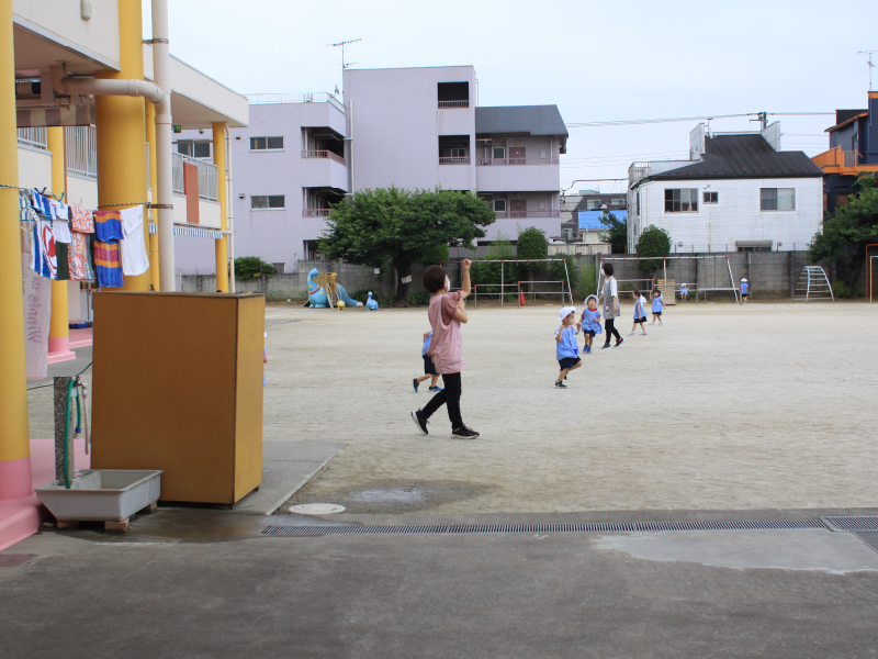 先生と一緒に戸外遊びを楽しむ預かり保育利用中の子どもたち